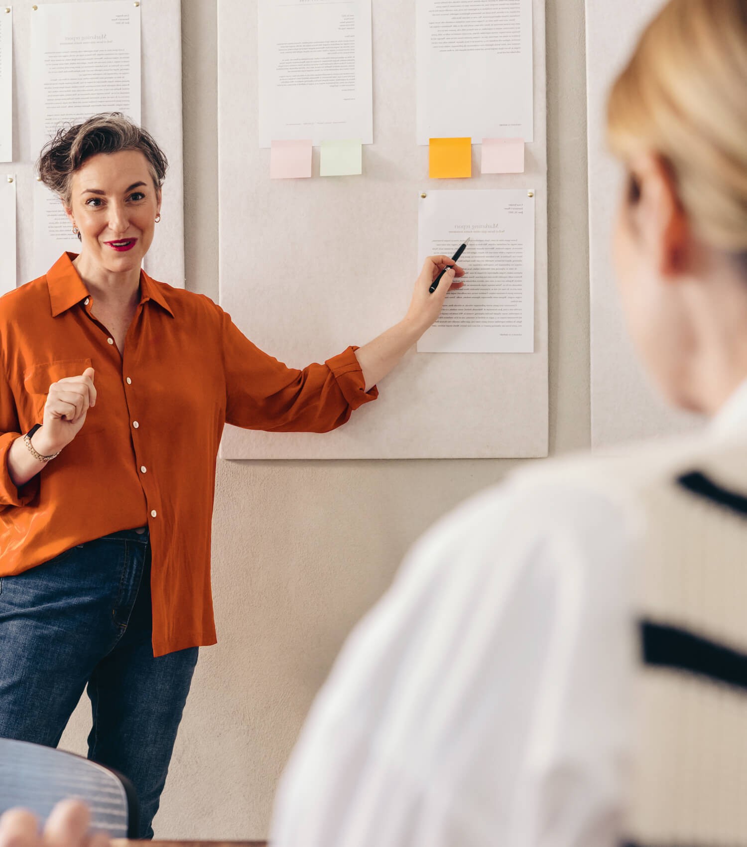 Woman pointing to sticky note on white board