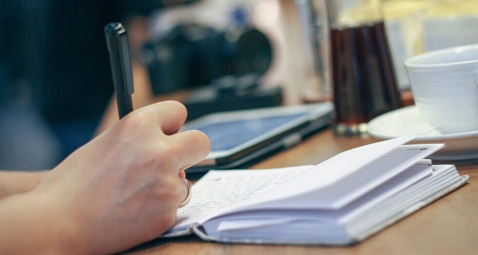 Someone writing in a journal by hand. Image by Pexels from Pixabay